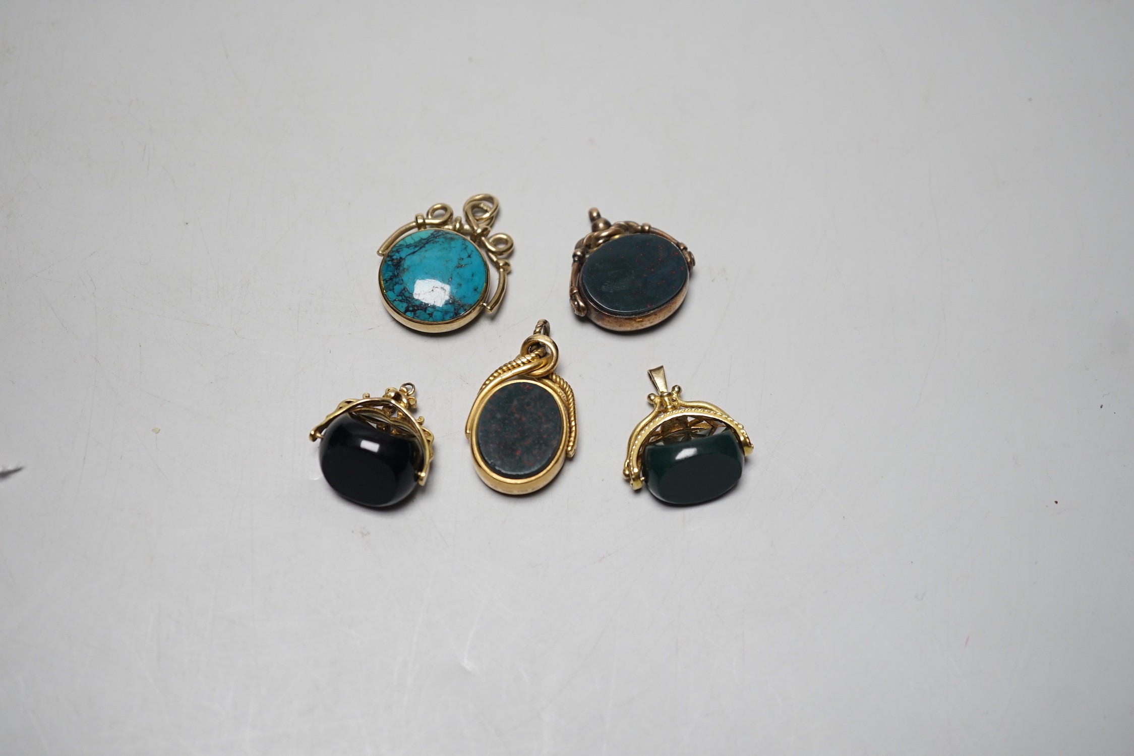 A late Victorian 18ct gold mounted bloodstone and carnelian set spinning fob seal, 36mm, a similar 9ct seal, a yellow metal and turquoise set fob seal and two later 9ct gold mounted seals.